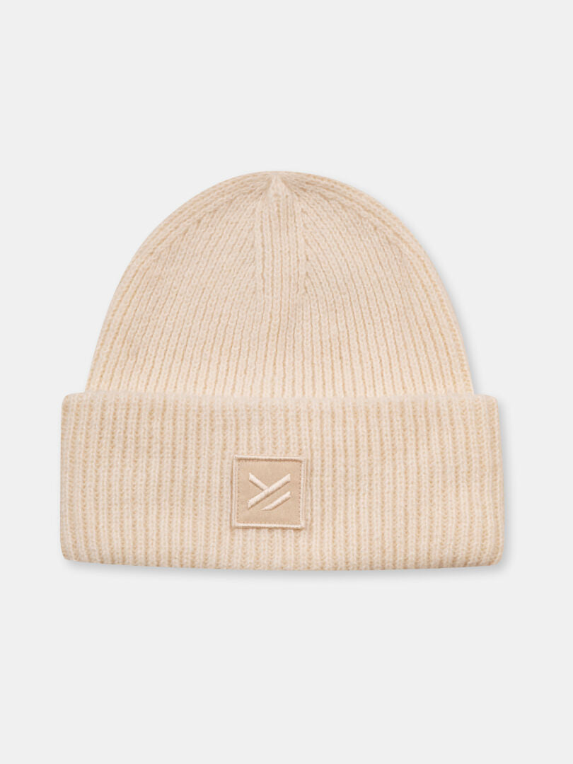 Beige Huurre Mössa från Halti med grovstickat ribbmönster, vikt kant och enkel patch framtill.