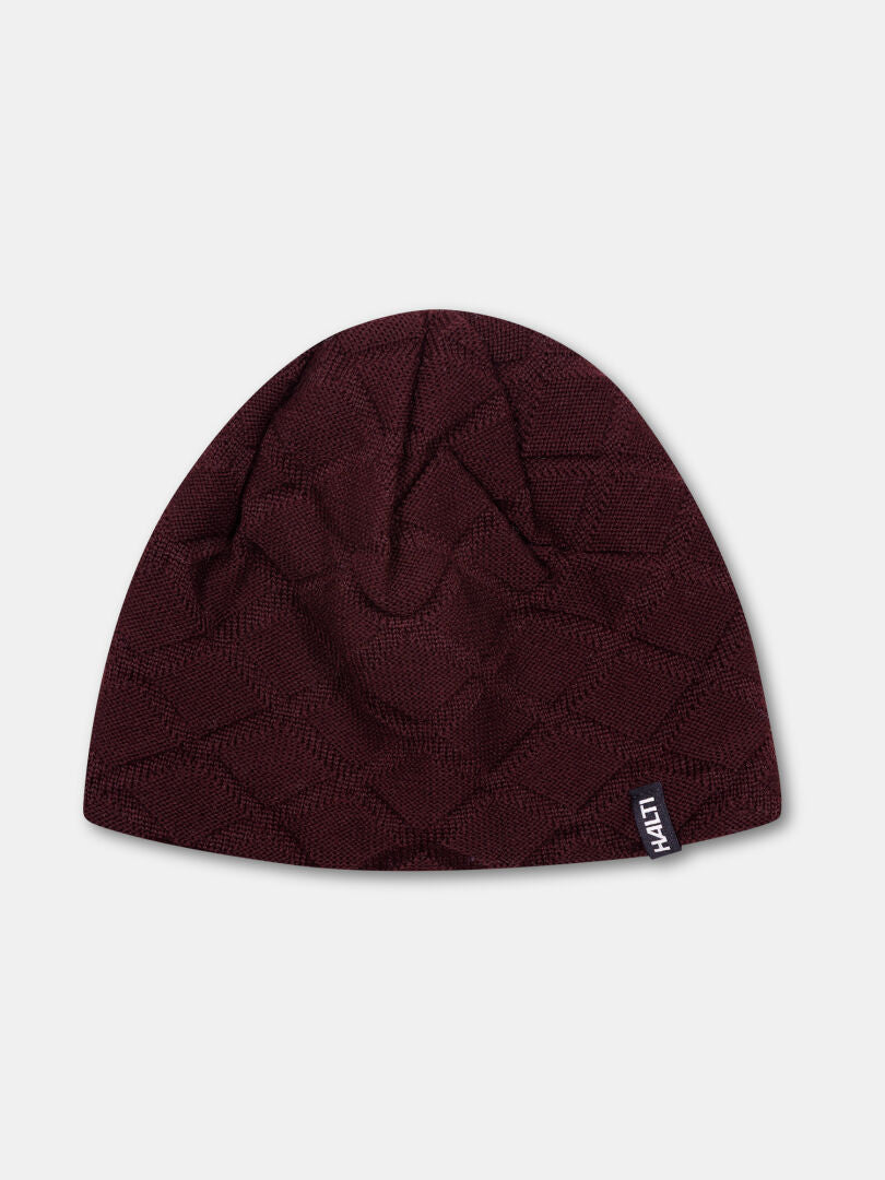 Halti Crostie Merinomössa är en vinröd hatt med ett subtilt geometriskt mönster och en liten svart HATTI-etikett.