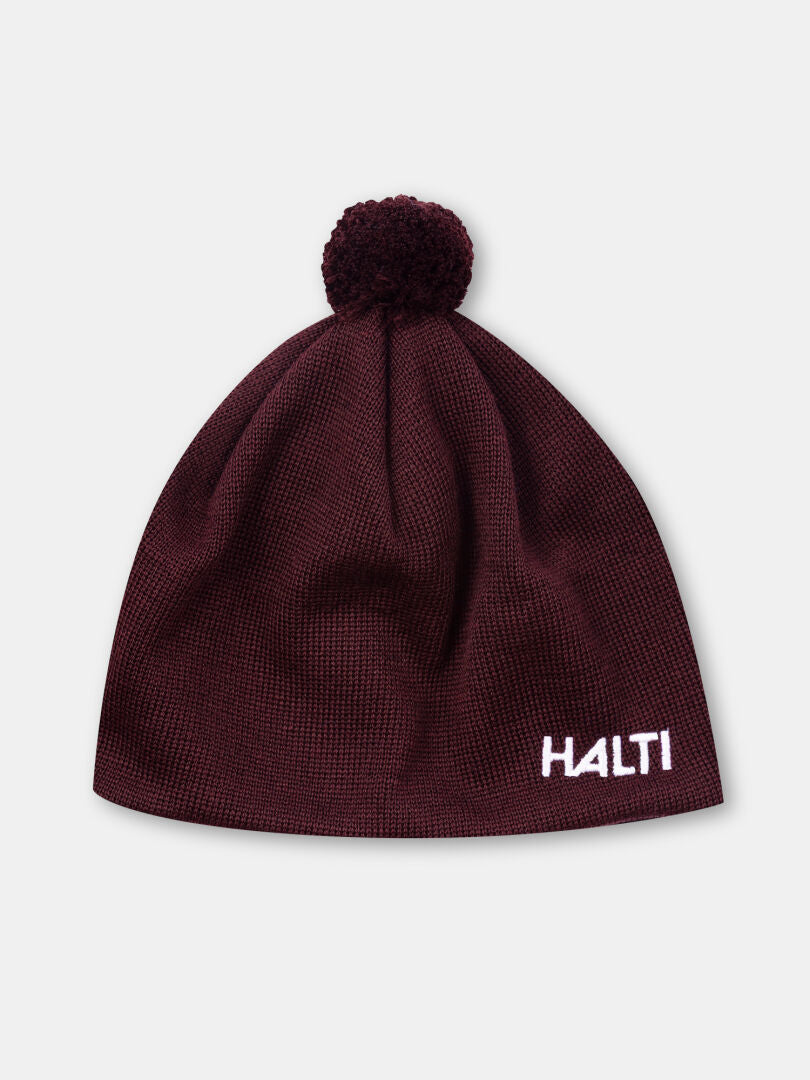 Peesi II Mössa by Halti: rödbrun mössa i merinoull med pom-pom och vitt HALTI-broderi på framsidan.