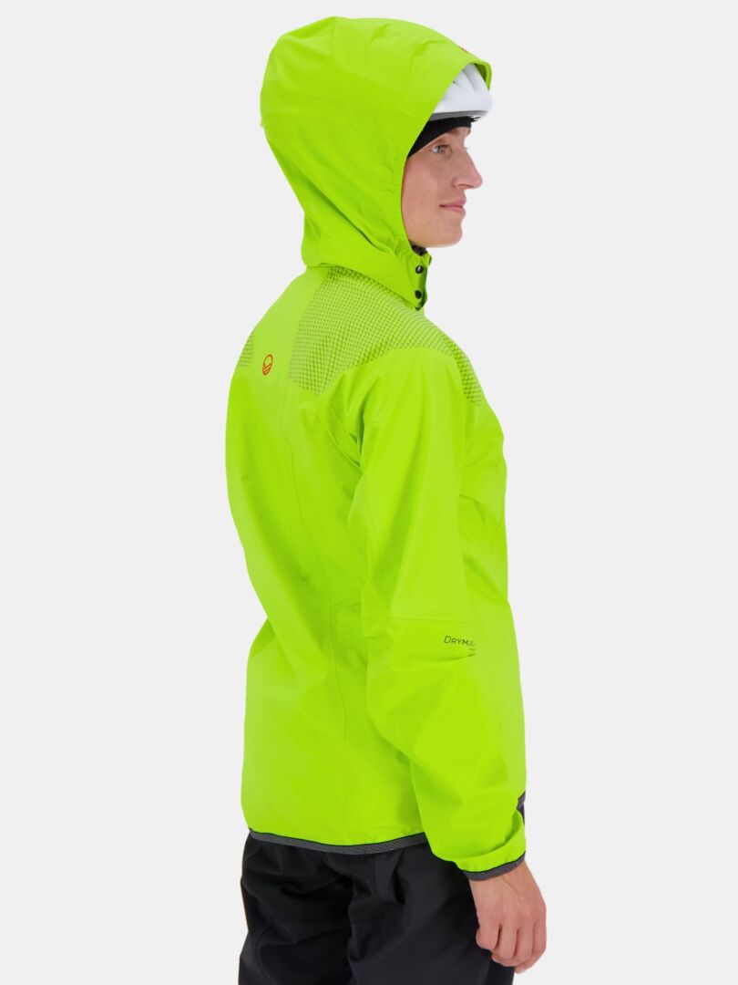 En person bär Halti Liike Dam 3L DrymaxX Sport Jacka i klargrönt, stående snett mot en slät bakgrund.