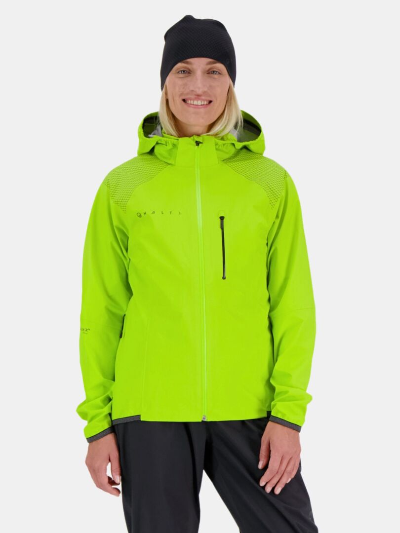 En person ler, redo för utomhusträning i Halti Liike Dam 3L DrymaxX Sport Jacka, svarta byxor och mössa.