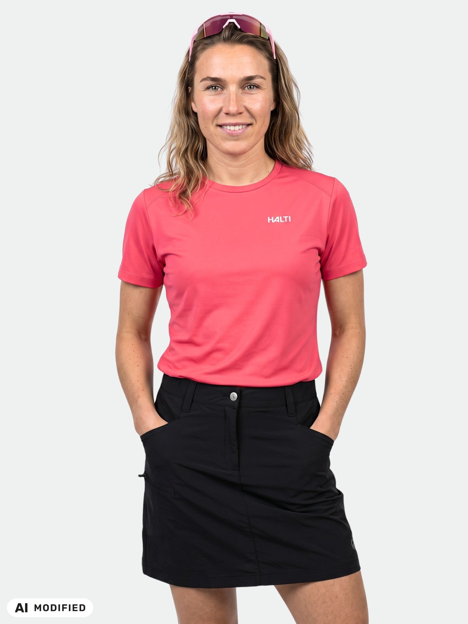 En person i en rosa Halti Salves T-shirt för damer och en svart kjol står vänd framåt med händerna i fickorna.