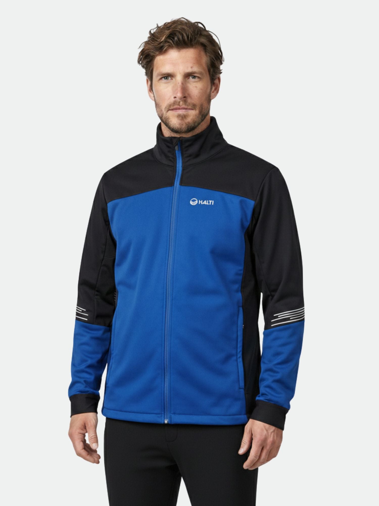 En man i Halti Siide Längdskiddräkt Herr står mot en vanlig ljus bakgrund.