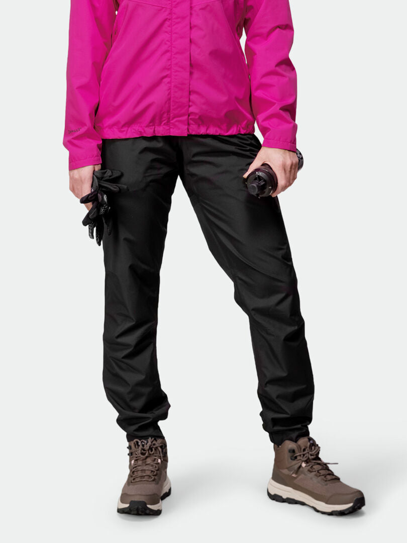 Person i en rosa jacka av återvunnen polyester och Halti Triant DX Cykelbyxor Dam, håller i handskar och en flaska.