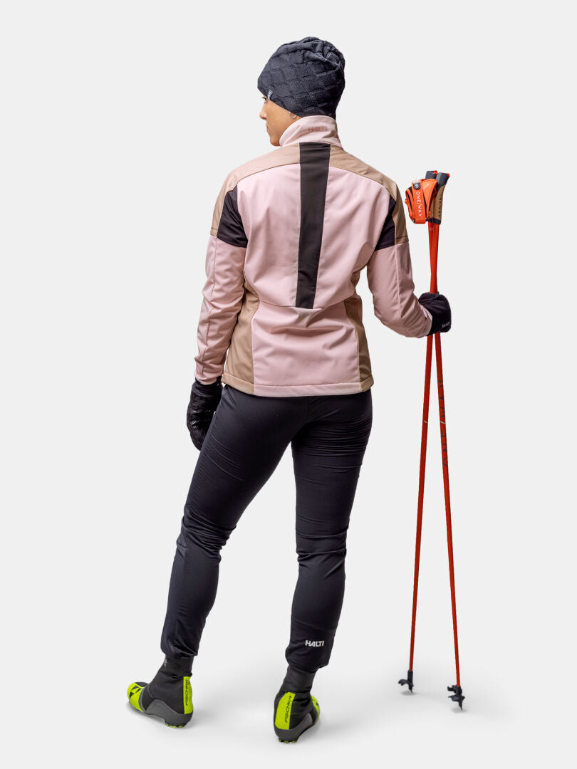 Iförd Halti Huuru Längdskiddräkt Dam, med röda skidstavar - perfekt för vinterträning och längdskidåkning.