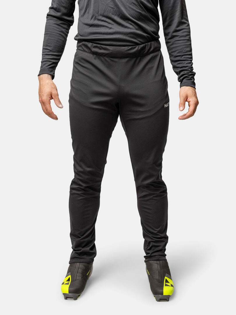 En person i Halti Framover Längdskidbyxor Herr, långärmad tröja och svarta skor med gula detaljer.