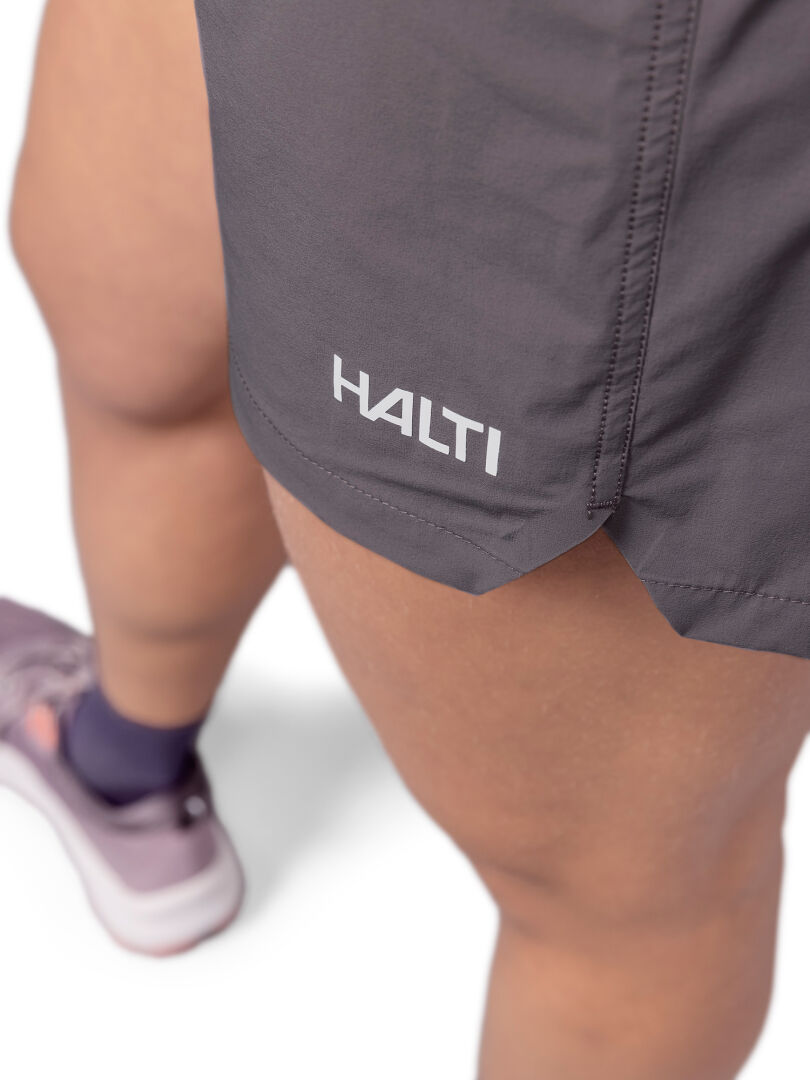 Närbild på en person i grå Halti Uurto Shorts Dam med Halti-logotyp, med snabbtorkande material.