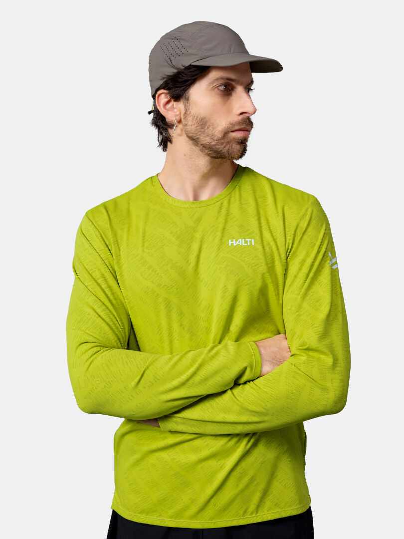 Man i grå keps och grön Halti Oulanka Träningströja Herr med UPF 50+ står med armarna i kors och tittar åt sidan.