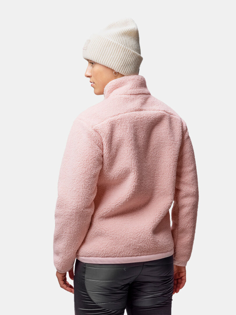 En kvinna med en vit stickad mössa och en rosa Halti Lumista Polar Fleecejacka, sedd bakifrån mot en enfärgad bakgrund.