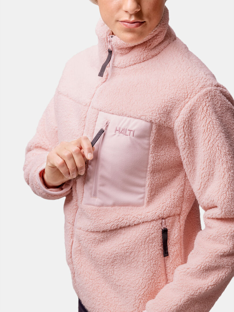 Person iklädd Lumista Polar Fleecejacka Dam från Halti, öppnar bröstfickan med Haltis logotyp synlig.
