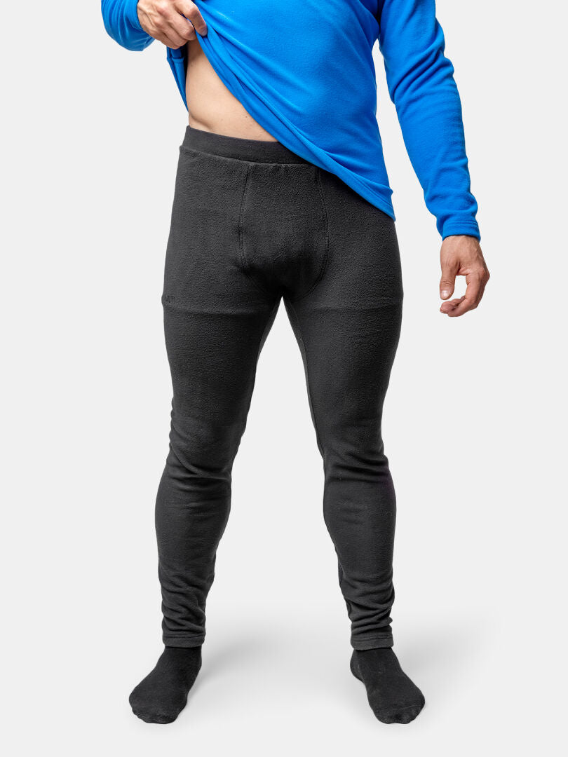 Person i blå långärmad skjorta och Halti Trone Fleece Byxor Herr lyfter upp skjortan för att visa mellanlagrets midja.