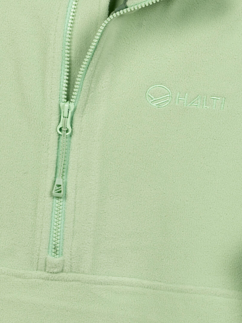 Närbild på Haltis Ossia Fleece Tröja Dam i ljusgrönt med halv dragkedja, fickor med dragkedja och bröstlogotyp.