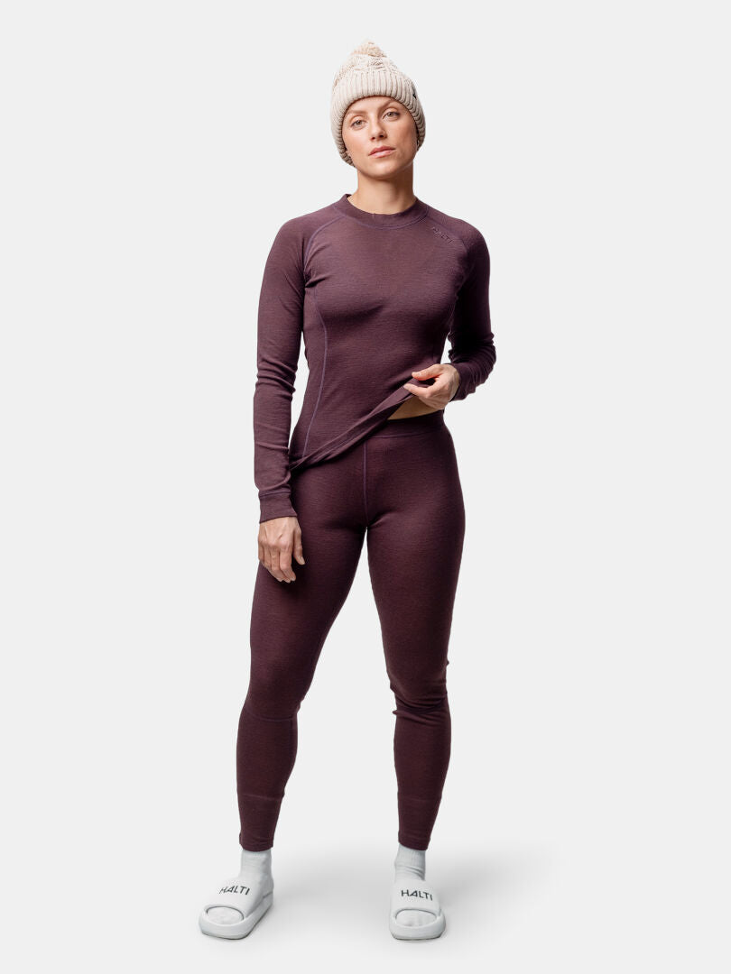 En person bär Halti Hossa II Merino Underställ Set Dam, vit mössa och tofflor mot en vanlig ljus bakgrund.