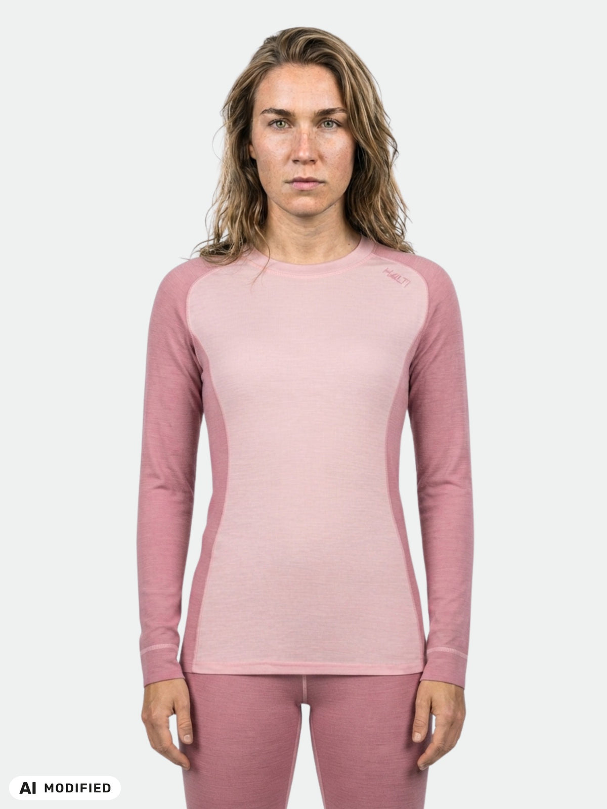 En kvinna bär Halti Hossa II Merino Underställ Set Dam, perfekt för träning i kallt väder, mot en enfärgad ljus bakgrund.