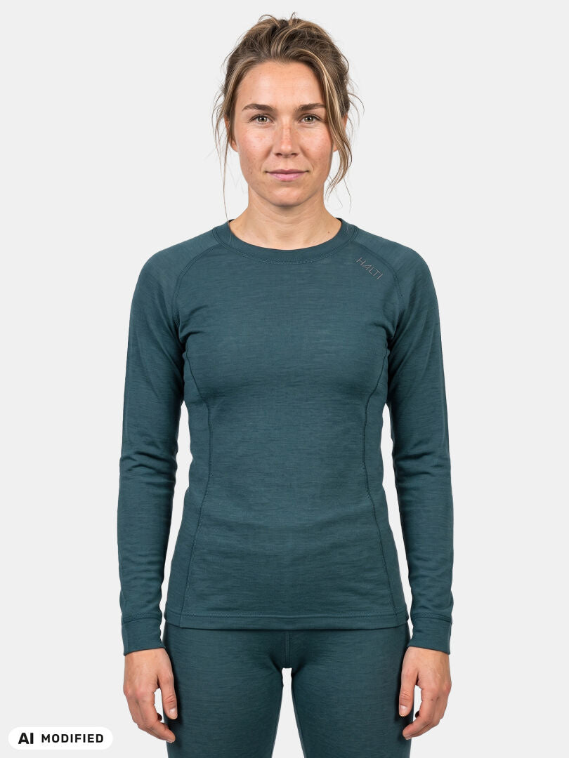 Kvinna i Hossa II Merino-underklädeset för dam från Halti, blågrön, mjuk merinoull, perfekt för friluftsliv mot vit bakgrund.