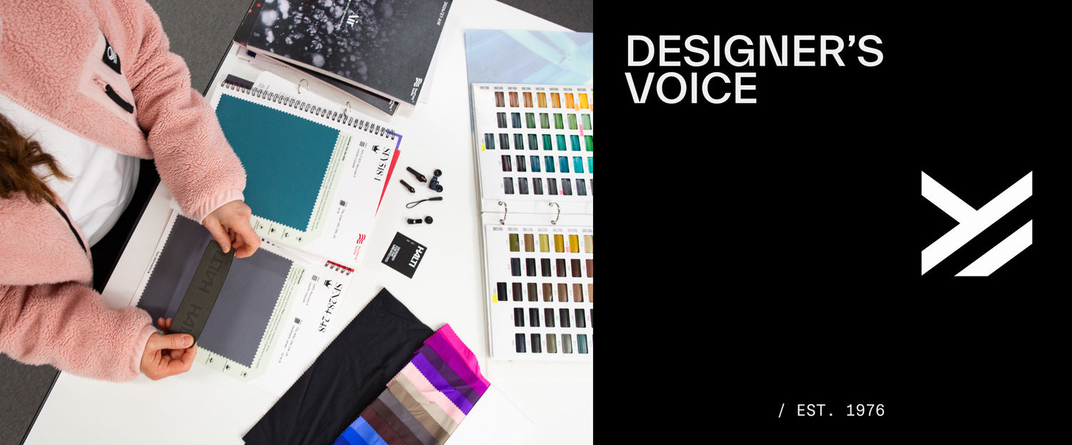 Person som granskar tyg- och färgprover på ett skrivbord, med broschyrer och designermaterial märkta DESIGNERS VOICE.