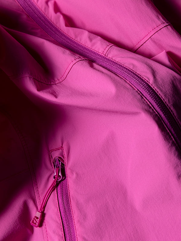 Närbild av en ljusrosa jacka med dragkedja och sömdetaljer på tyget.