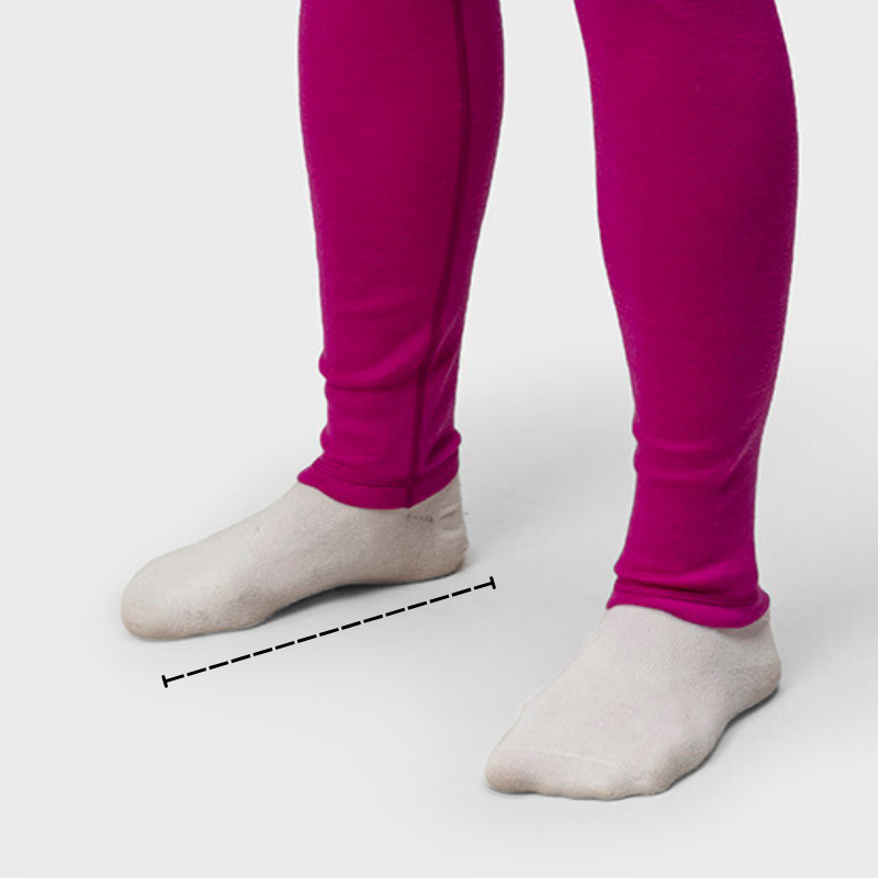 Person i magentafärgade leggings som står med fötterna isär, iförd ljusa strumpor, med en streckad mätlinje mellan fötterna.