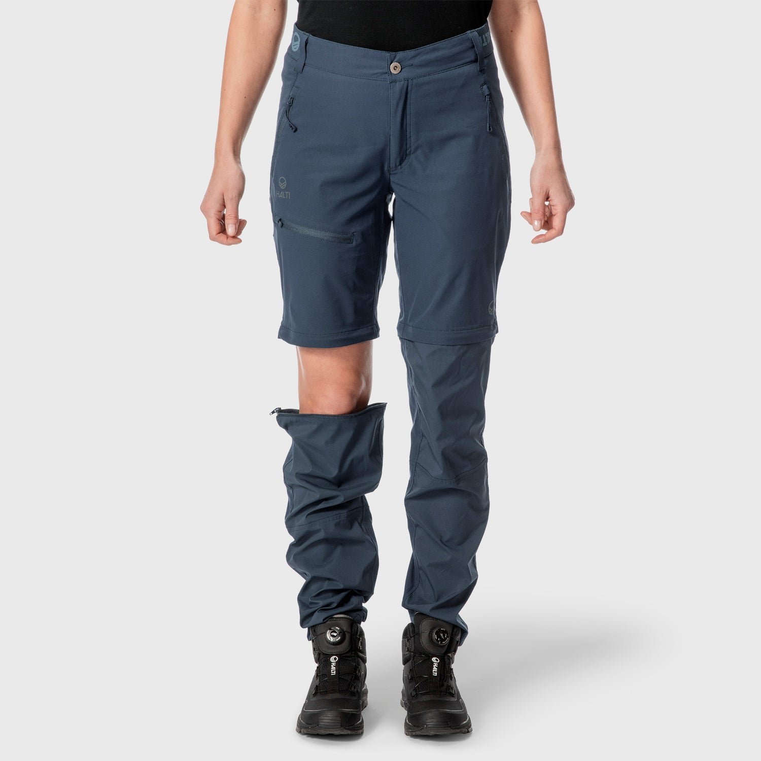 Person klädd i blå byxor med dragkedja och ena byxbenet delvis borttaget, vilket avslöjar shorts under.