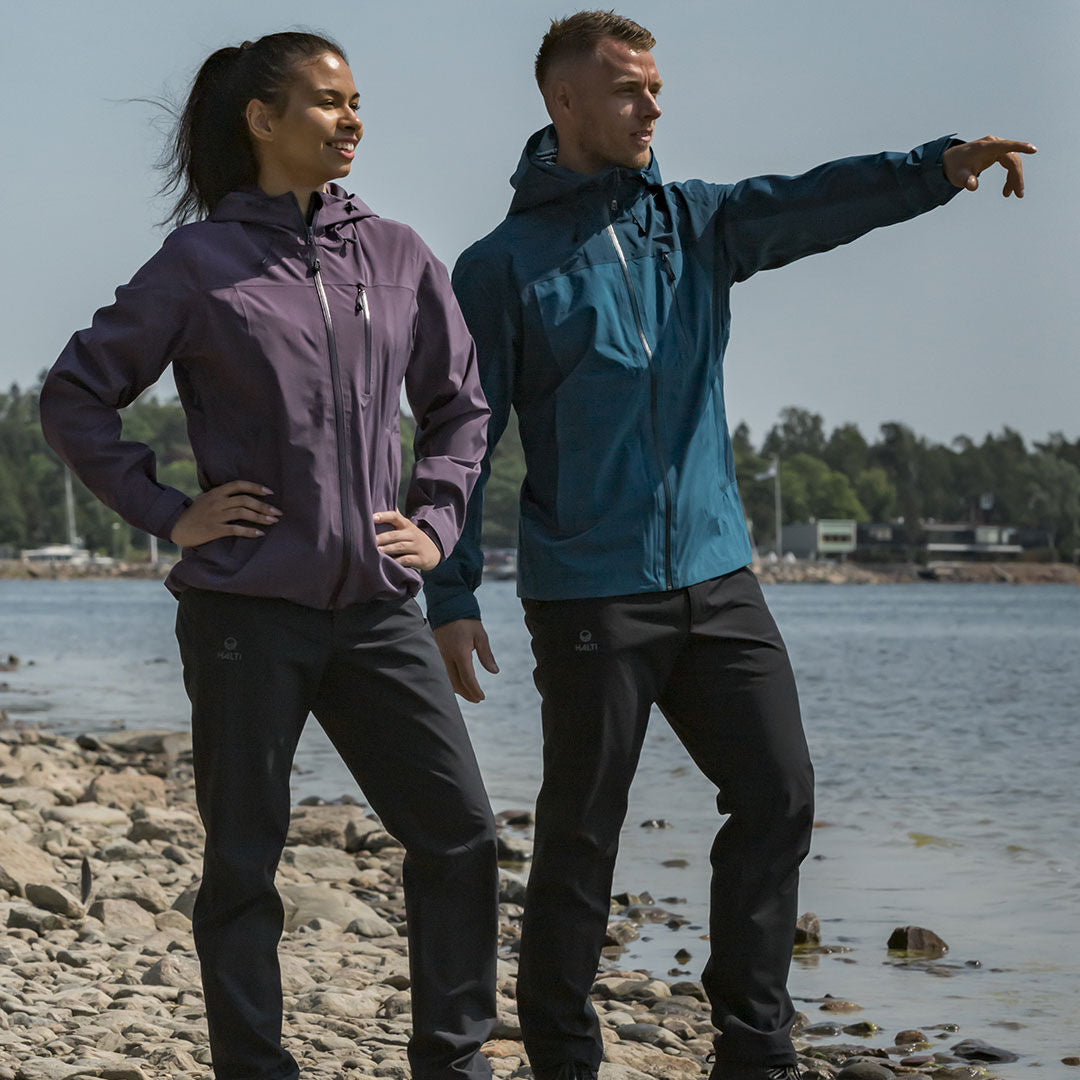 Två personer i Halti Leisti DX Skalbyxor Dam står på klippor; den ena pekar framåt medan de båda tittar ut i fjärran.