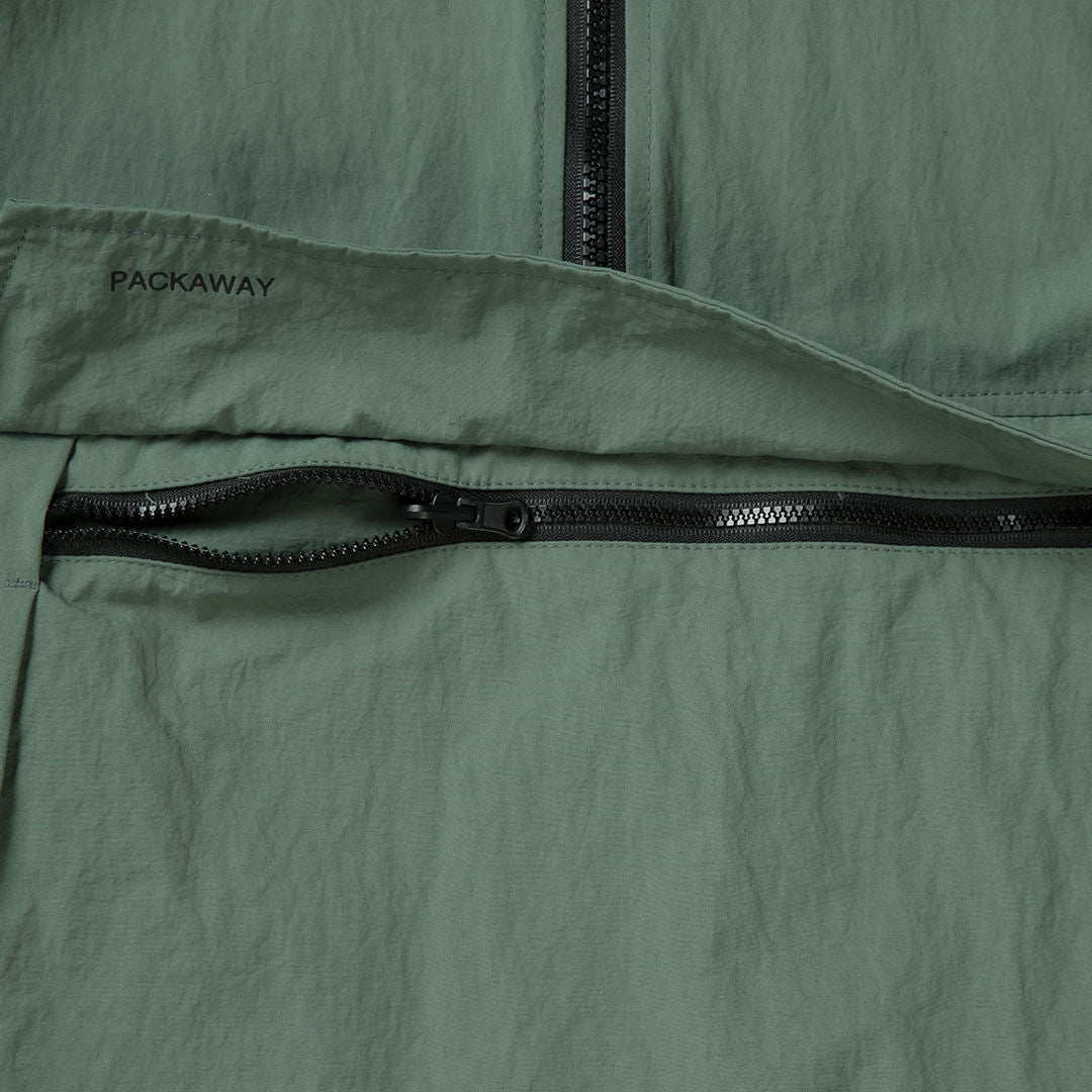 Närbild på Halti Blosis Unisex Anorak i grönt, med två svarta dragkedjor och PACKAWAY på återvunnet material.
