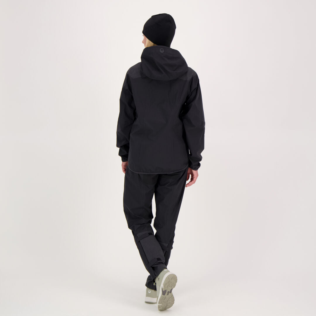 Person i svart luvjacka och Halti Liike Dam 3L DrymaxX Sport Byxor står vänd bort mot en ljus bakgrund.