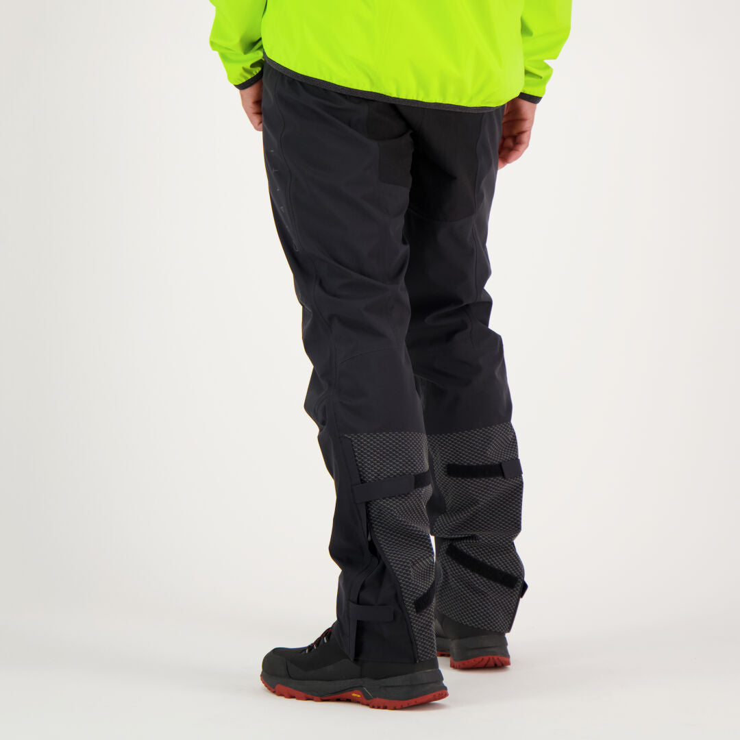 Person som bär Halti Liike Herr 3L DrymaxX Sport Byxor i svart återvunnen polyester och svarta stövlar, sedd bakifrån.