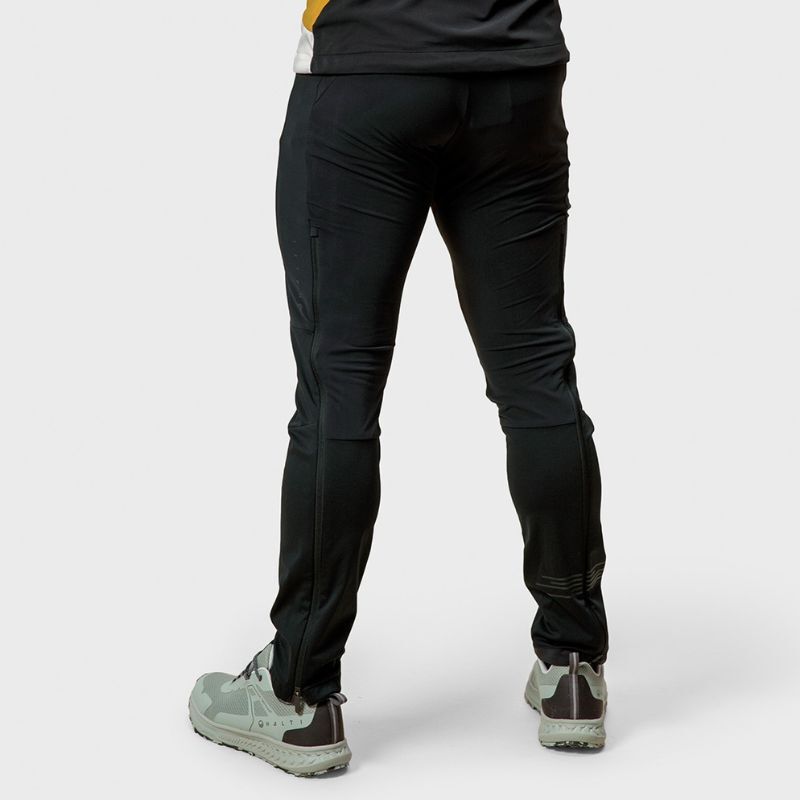 En person i Halti Veloce Längdskidbyxor Herr (Stormwall® stretch) står bortvänd mot en vanlig bakgrund.
