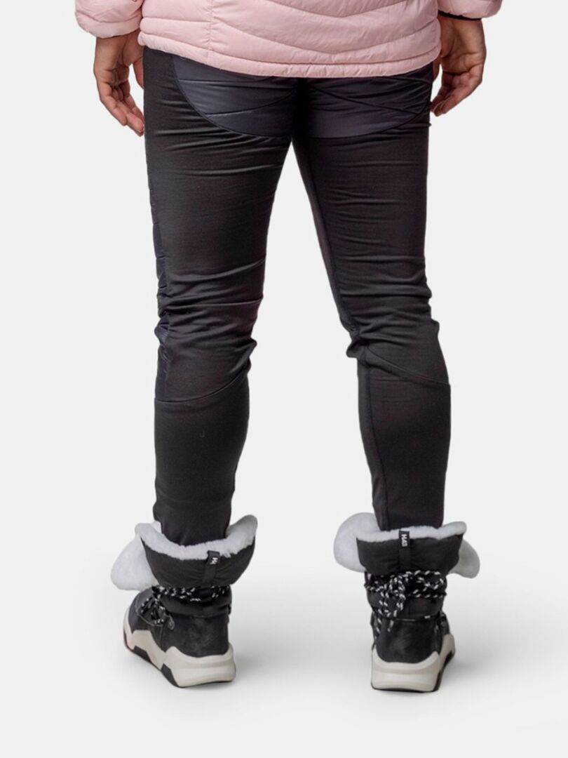 En person i svarta byxor, Halti Jeti DX Vinterkänga Dam, och en ljusrosa jacka står mot en vit bakgrund.