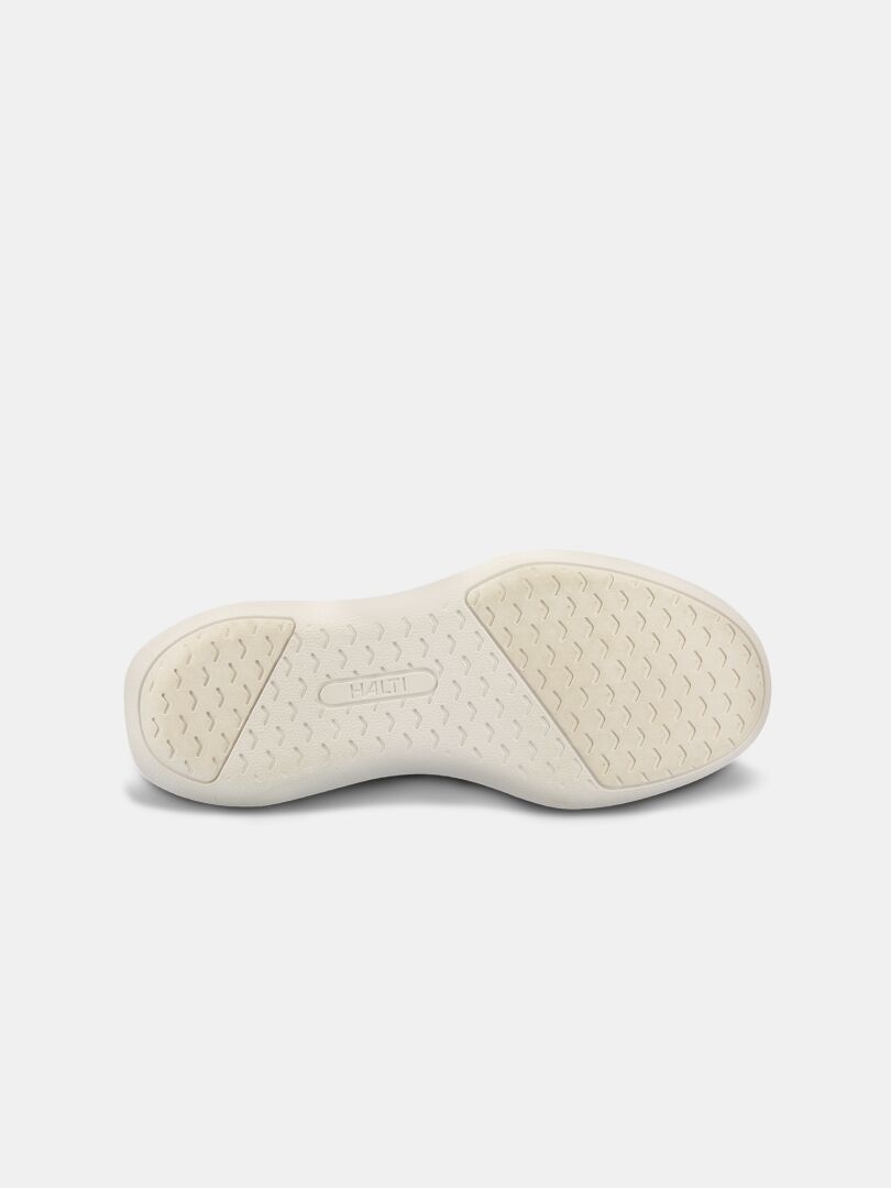 Den vita gummisulan med textur på Halti Snabb 2 StepIn Sneaker Dam är vänd uppåt mot en vit bakgrund.