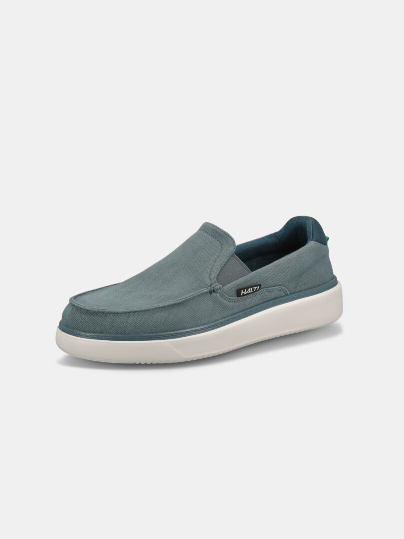 Halti Lido Canvas Skor Herr: blå slip-on loafers med vit sula, perfekta sommarskor för män mot vit bakgrund.