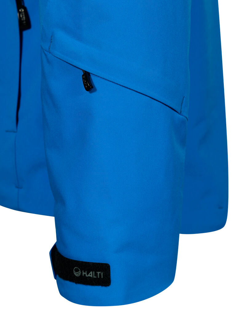 Närbild på en blå Vertica DX Skidjacka Herr-ärm med blixtlåsförsedd ficka och svart Halti-logotyp på ett kardborreband.