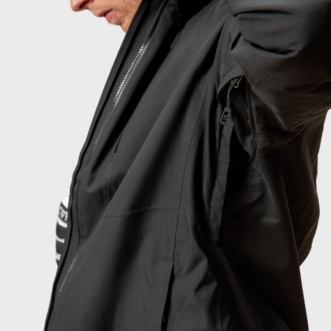 En person drar upp dragkedjan under armen på en Halti Vertica DX Skidjacka Herr och visar en randig skjorta under.