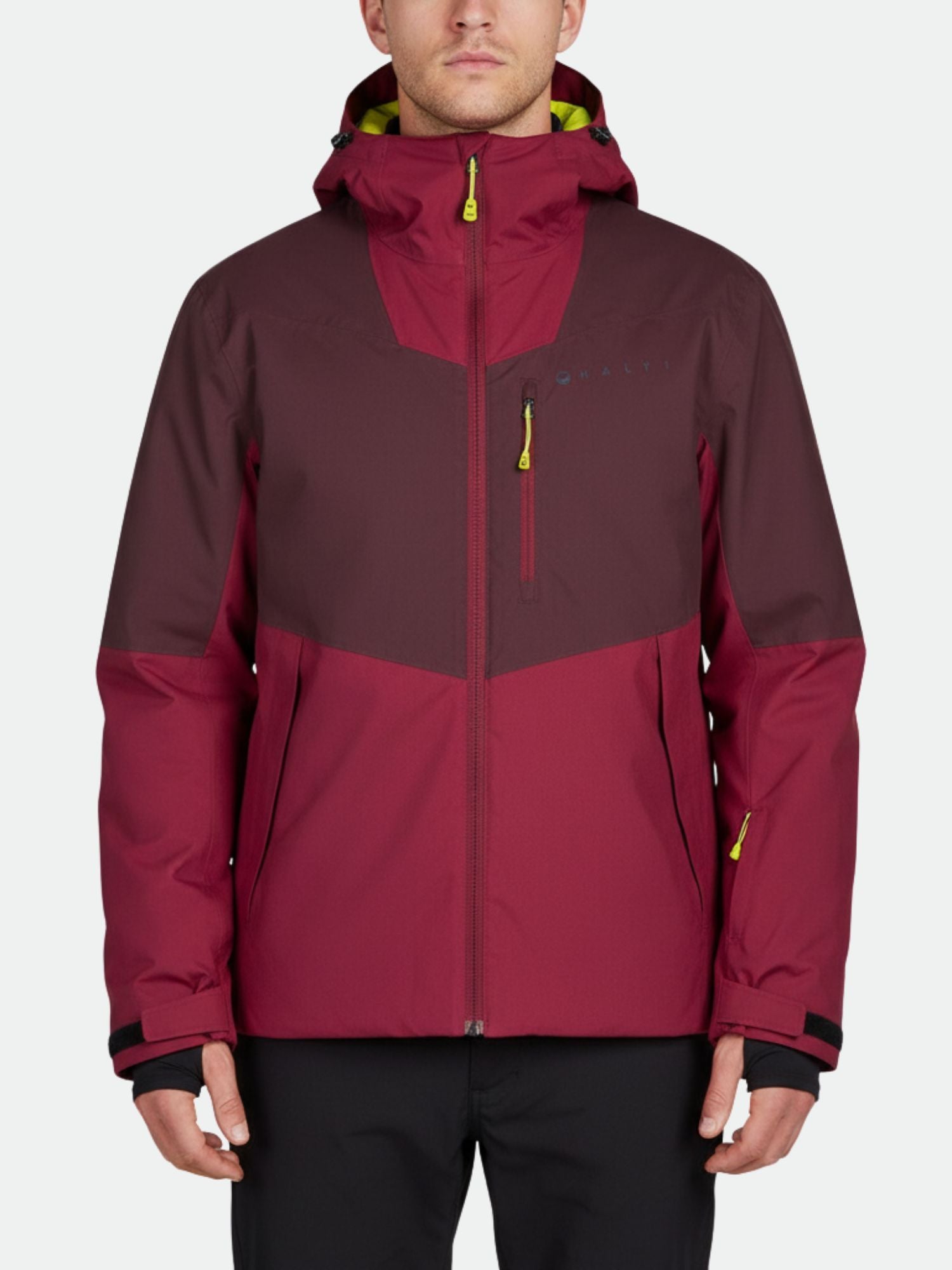 En person klädd i en rödbrun och röd Halti Wedeln DrymaxX Skidjacka Herr med fickor med dragkedja, vänd framåt.
