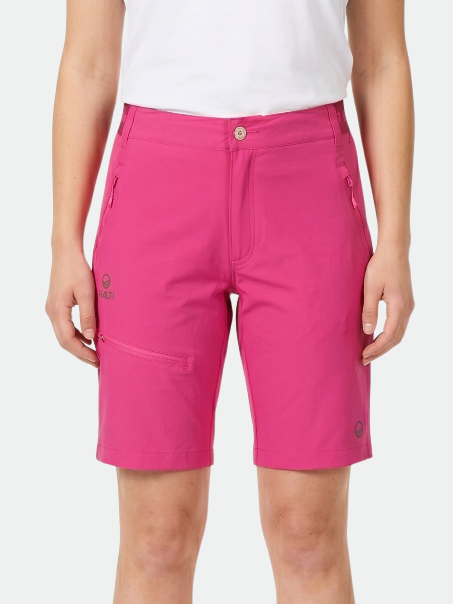 En person bär ljusrosa Halti Pallas Dam X-stretch Lite Shorts och en vit skjorta mot en enfärgad bakgrund.