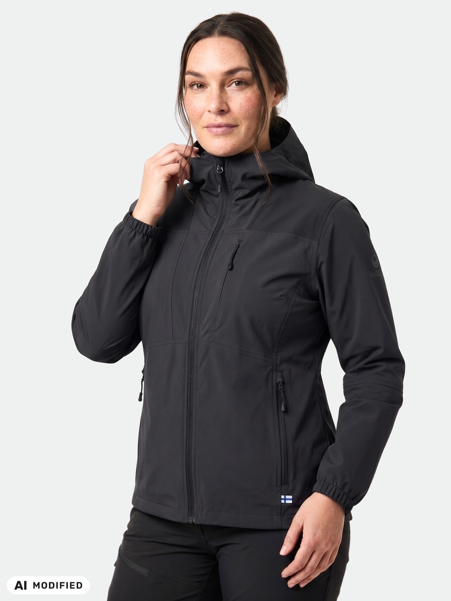 En kvinna i en Halti Pallas II Plus Dam x-stretch-jacka står framför en enfärgad ljus bakgrund.