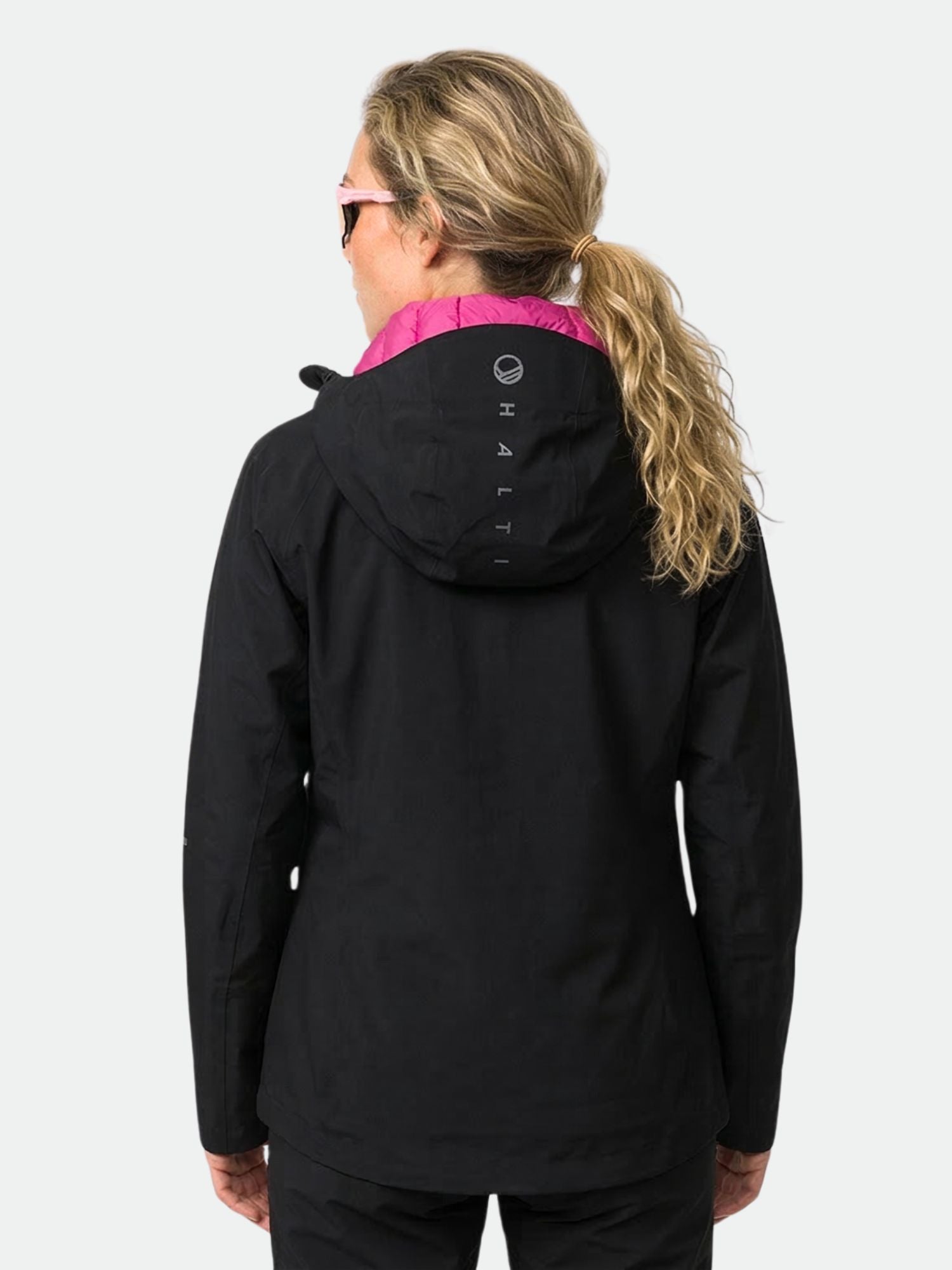 En person med blont hår i hästsvans bär en Halti Kaarna Dam DrymaxX 3L Skaljacka, sedd bakifrån.