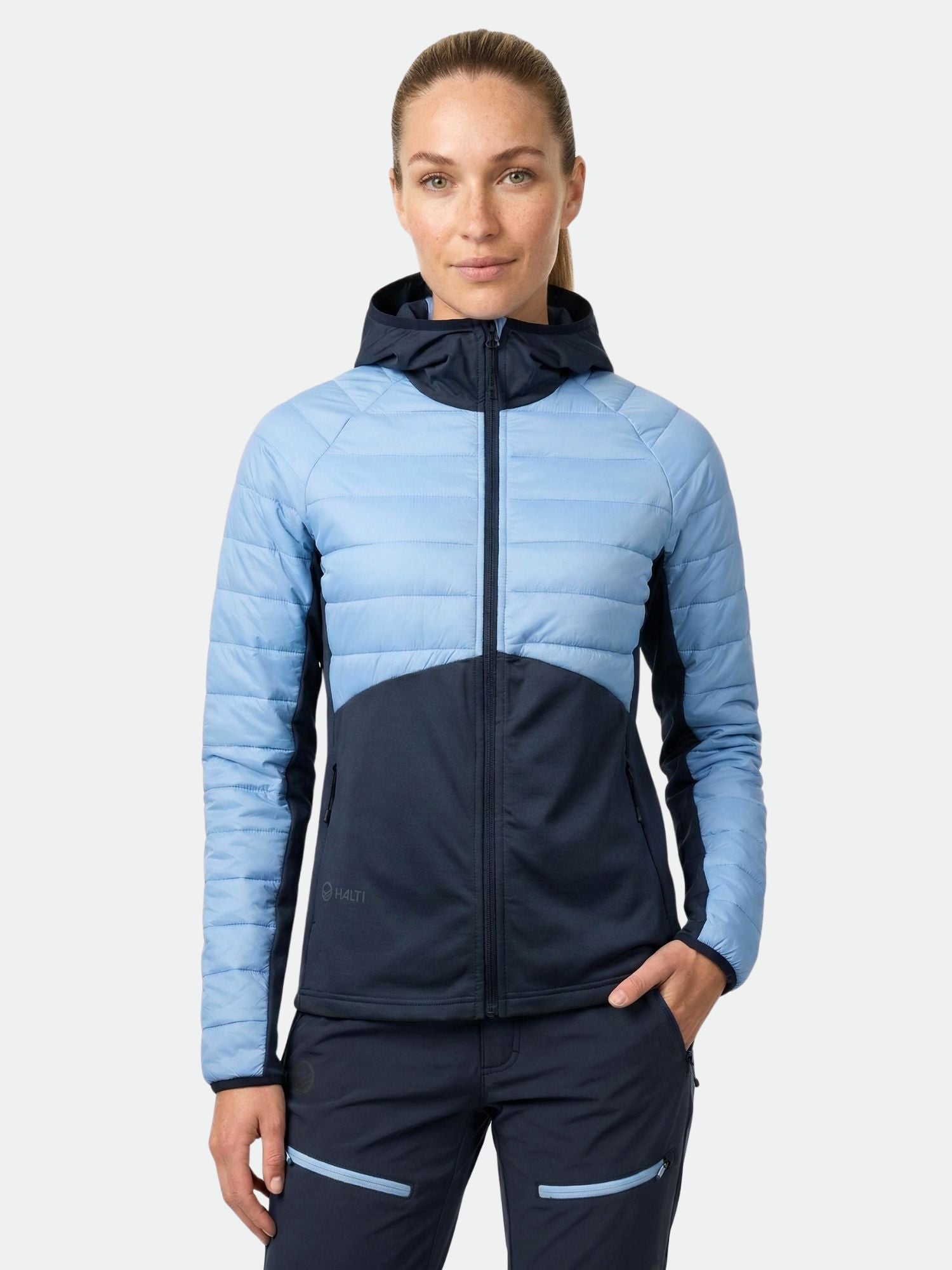 En kvinna i ett Halti Veidnes Dam Mellanlager står vänd framåt med händerna i fickorna.