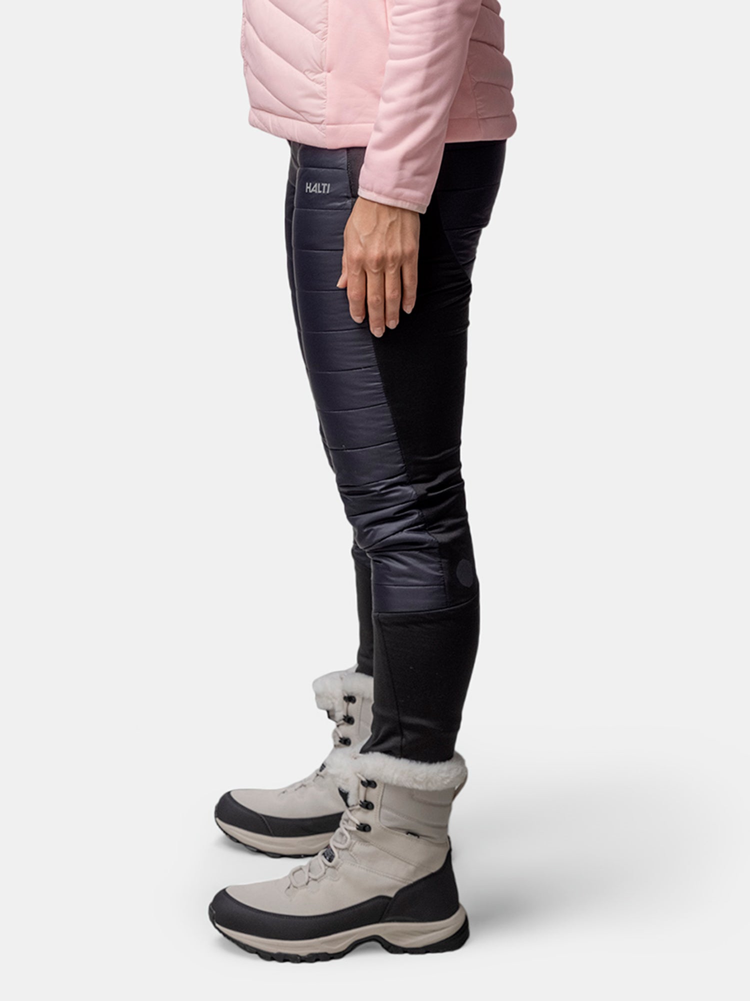 Person som står på sidan i rosa jacka, Halti Veidnes Lättvaddrade Byxor Dam, och ljusgrå pälsfodrade vinterstövlar.