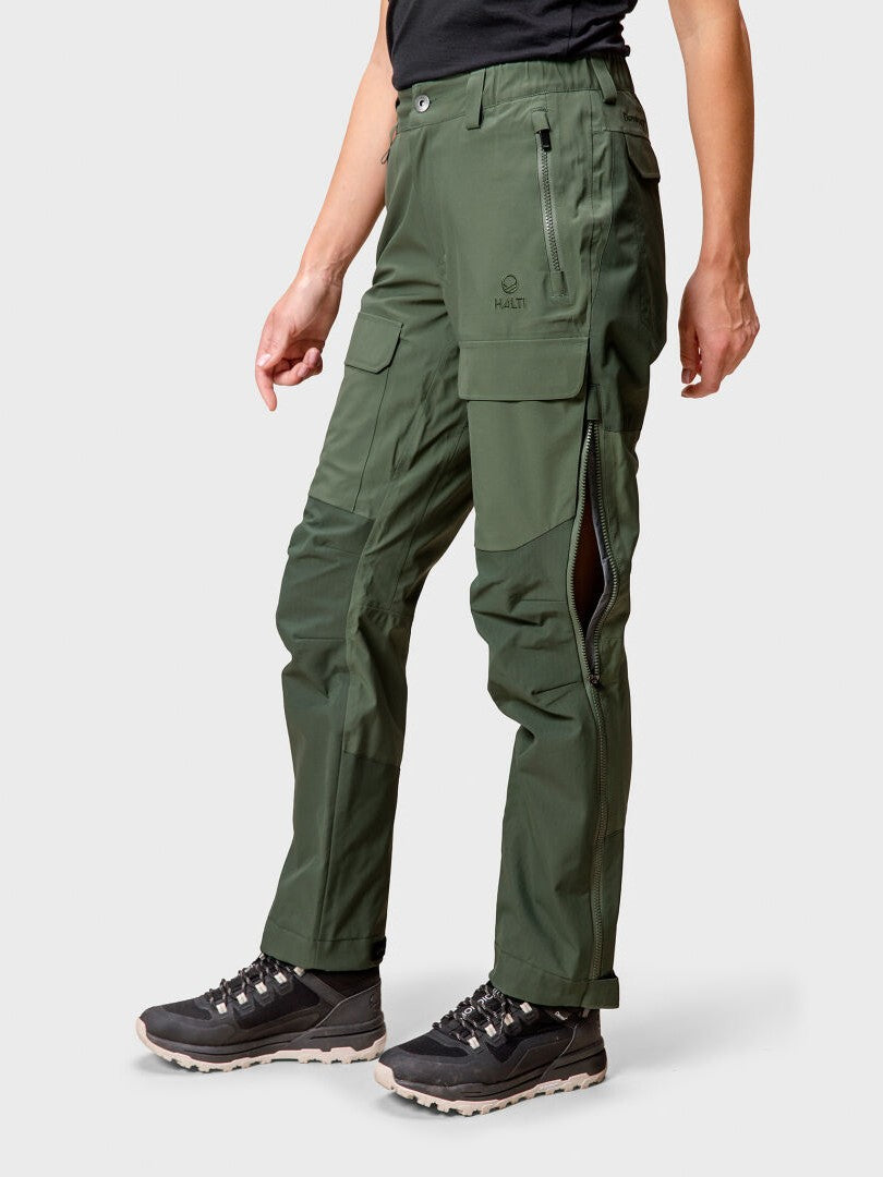 En person klädd i Halti Hiker DrymaxX 3L Ventilated Byxor Dam och svarta vandringsskor, mot en ljus bakgrund.