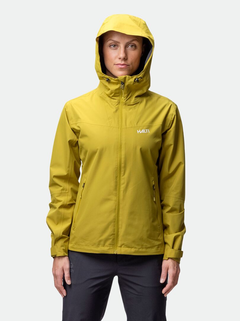 Person med gul Halti Forter DX Skaljacka Dam, stående mot en ljus bakgrund.