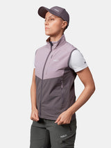 Kvinna i Halti Pallas Evo X-stretch Väst, vit t-shirt, grå keps och mörka byxor står i sidled med händerna på höfterna.