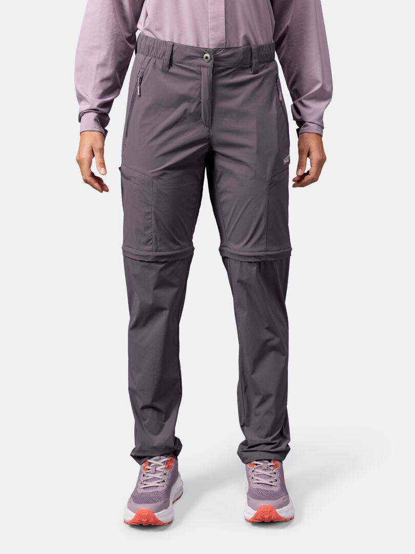 Person klädd i Halti Pallas Cool Stretch Zip-off Byxor Dam, matchande långärmad topp och lila sneakers vänd framåt.