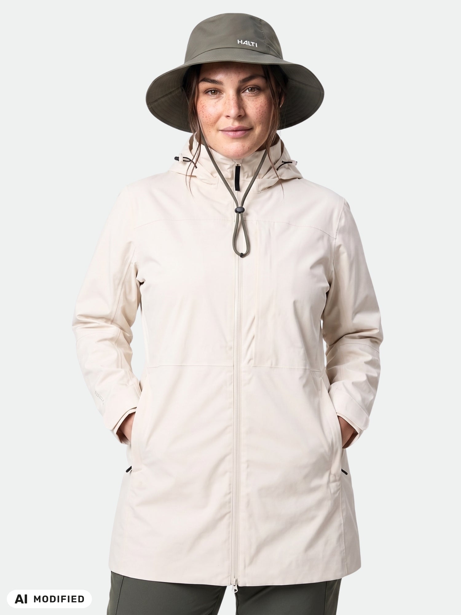 En person klädd i en ljus Kallas DX Parka Plus Dam från Halti och en bred hatt står vänd framåt med händerna i jackfickorna.