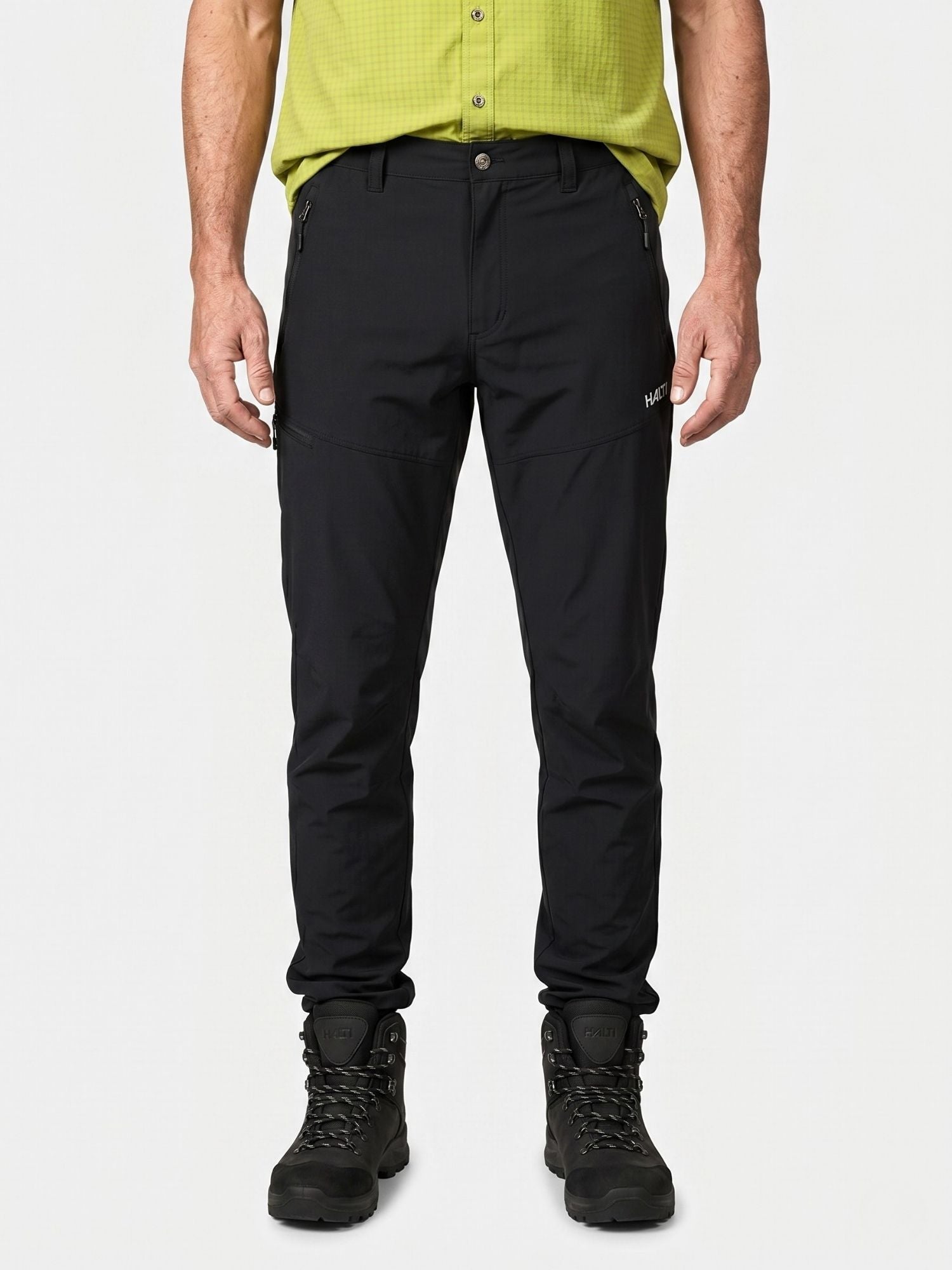 En man i grönt och Pallas Cool X-stretch Byxor Herr från Halti står vänd framåt mot en vit bakgrund.