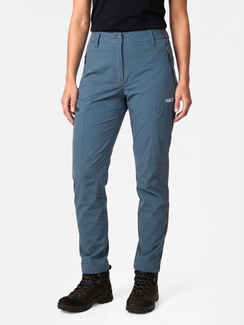 En person bär Halti Pallas Cool X-stretch Byxor Dam, svarta stövlar och en svart skjorta mot en vanlig ljus bakgrund.