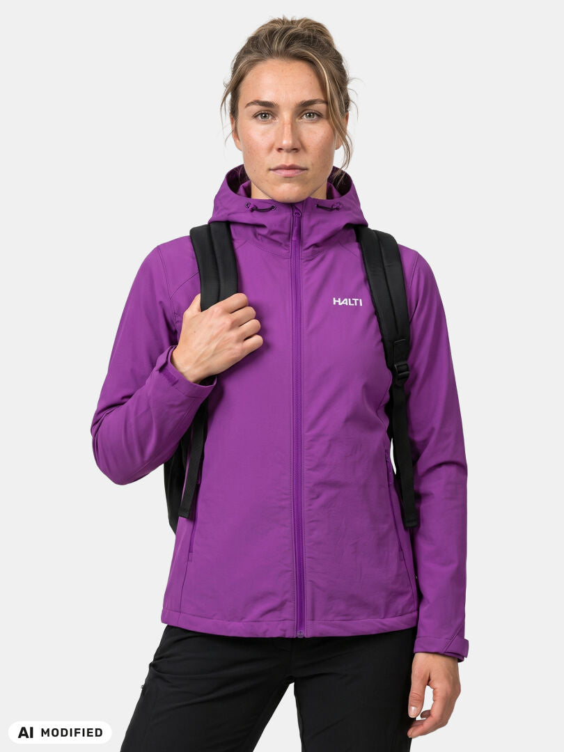En person klädd i en lila Halti Finholma X-stretch Jacka Dam och med en svart ryggsäck står vänd framåt mot en enfärgad bakgrund.