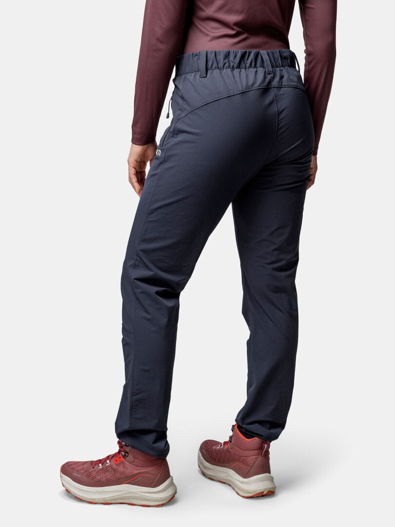 Person klädd i Halti Finholma X-stretch Byxor Dam, rödbrun långärmad skjorta och rödbruna sportskor, bakifrån.