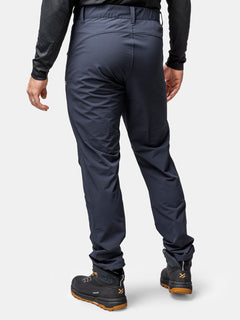 En person klädd i Halti Finholma X-stretch Byxor Herr, en svart långärmad skjorta och vandringskängor, sedd bakifrån.