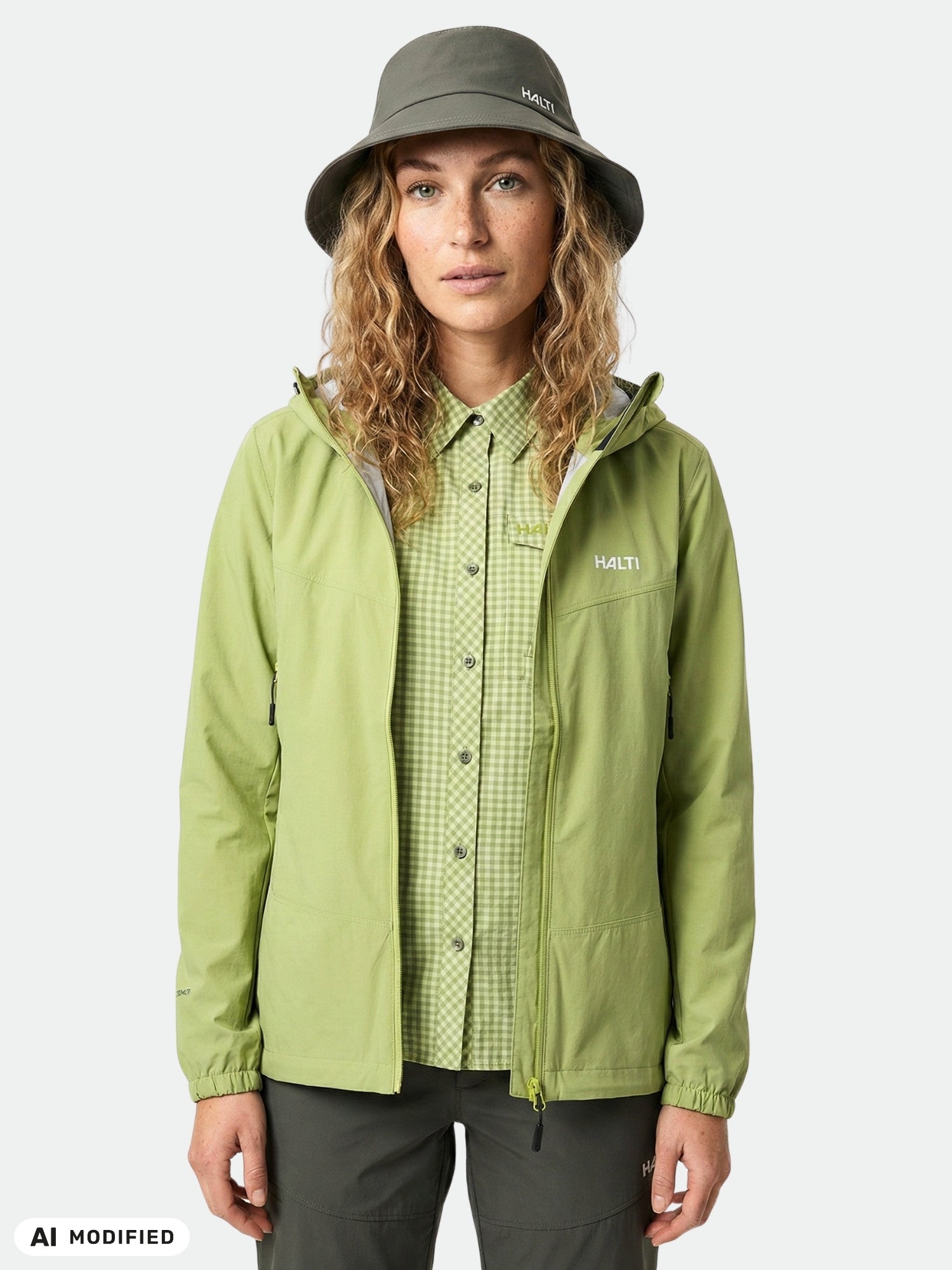 En kvinna bär en Halti Samoy Funktionsskjorta och en grå bucket hat med UPF 50+, stående mot en vit bakgrund.